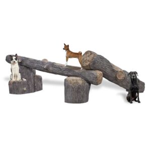 Three dogs interact with a playground seesaw shaped and textured like wooden logs; two dogs sit on either end while one stands in the middle.