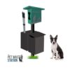 A green and black pet waste station with bag dispensers and bins, next to a small black and white dog sitting. "The Pet Waste Station" logo appears in the bottom left corner.