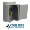 A gray metal wall-mounted box with an open door reveals a blue-handled valve inside. Below is the Cool Dog Water Founatin - STE - Pet Hose Bib Attachment logo featuring a dog illustration.