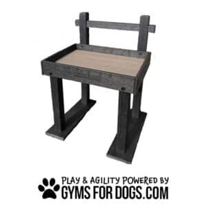 A sturdy black dog agility table with a wooden top, labeled "DOGTASTICFOR DOGS," and the text "Play & Agility Powered by Gyms For Dogs.com" with a paw print below.