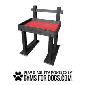 A black and red dog agility platform with the words "Gyms For Dogs" on the side. Text below reads "Play & Agility Powered by GymsForDogs.com" with a paw print graphic.