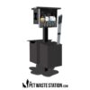 A black pet waste station with bag dispensers, a waste bin, and two scooper tools. The station displays instructions and is labeled with ThePetWasteStation.com logo at the bottom.