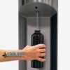 A hand holds a black reusable bottle under a water dispenser as it fills. The image features a "Cool Dog Water Fountains" logo in the lower left corner.