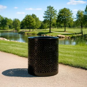A black trash can with a flat-top lid, sunlight casting shadows on a pathway by a small pond in a green park.
