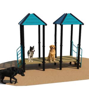 Two dogs are sitting on a playground structure with platforms and peaked roofs, while a third dog walks on the ground nearby. The playground is set on a brown surface with a white background.